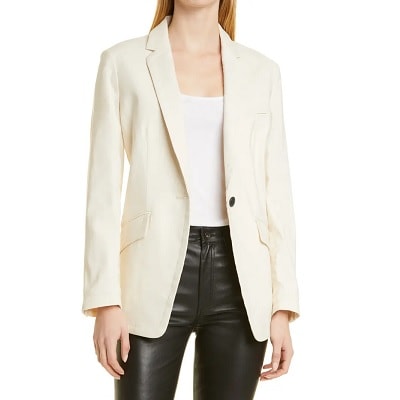 A lady wearing a cream colored suit with black pants