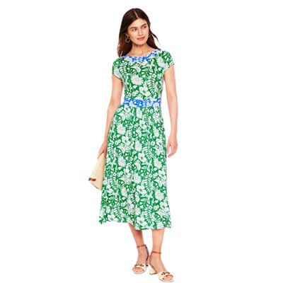 A woman wearing a green floral midi dress and sandals