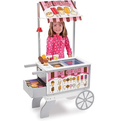 A little girl playing with a  Snacks and sweets toy food cart