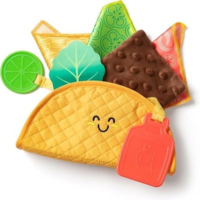 A yellow smiling soft toy in the shape of a taco, with taco "fillings" around it