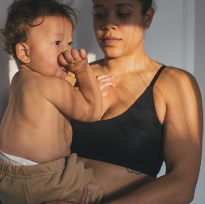 A mother wearing The Multitasking Maternity Bra, with her child