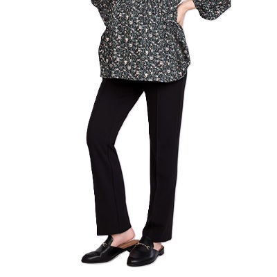 A pregnant woman wearing a black floral top, black maternity pants, and black mules
