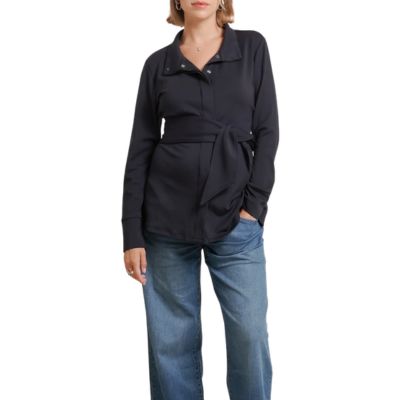 A woman wearing a black maternity jacket and blue jeans with brown flats