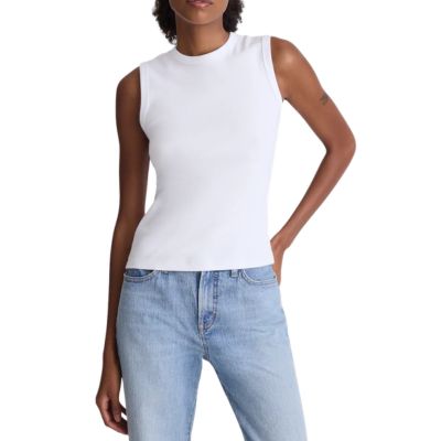 A woman wearing a white sleeveless top and light blue jeans