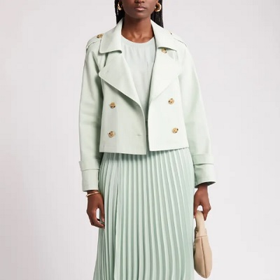 A woman wearing a mint-colored jacket and mint pleated skirt