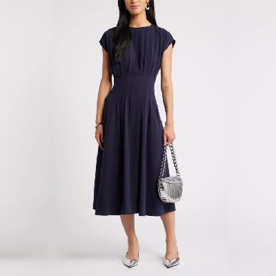 A woman wearing a navy dress and silver kitten heels
