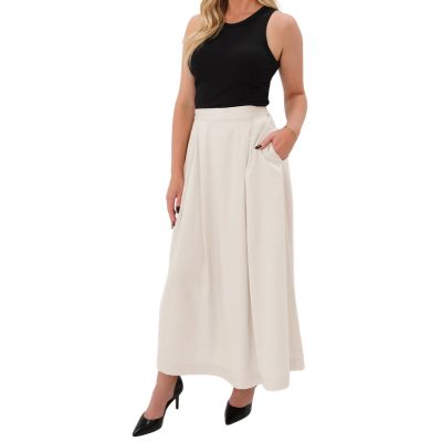 A woman wearing a black tank top, ivory maternity maxi skirt, and black slingbacks