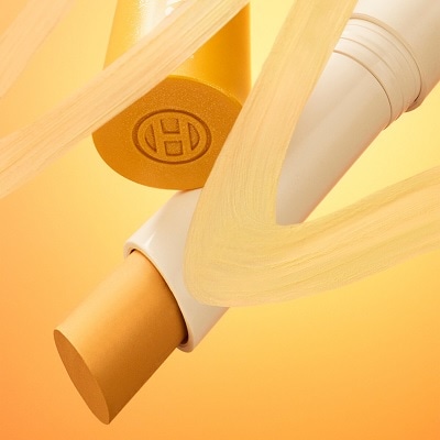 An open tube of OLEHENRIKSEN Banana Bright+ Vitamin CC Eye Sticks, behind a swatch of the product

