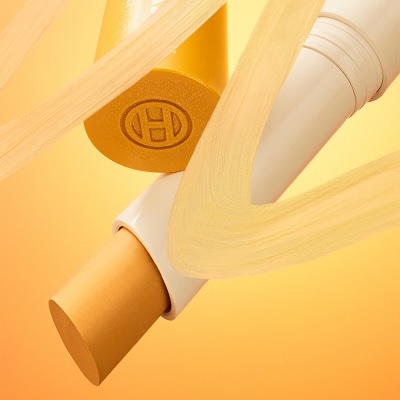 An open tube of OLEHENRIKSEN Banana Bright+ Vitamin CC Eye Sticks, behind a swatch of the product