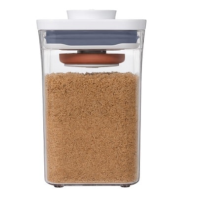 A clear container with a white lid and terracotta disc under the lid, filled with brown sugar 