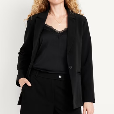 A woman wearing a black blazer with black lace-trim top and black pants