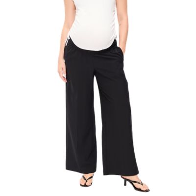 A woman wearing black maternity pants, a white top, and black heels