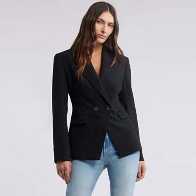 A woman wearing a black blazer and light blue jeans