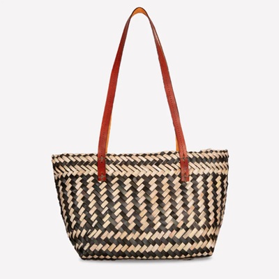 A black-and-white woven palm tote with a brown leather handle