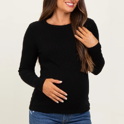 A woman wearing a black long sleeve top with denim pants
