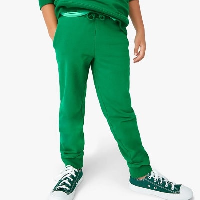 A boy wearing green pants, a green shirt, and green-and-white sneakers