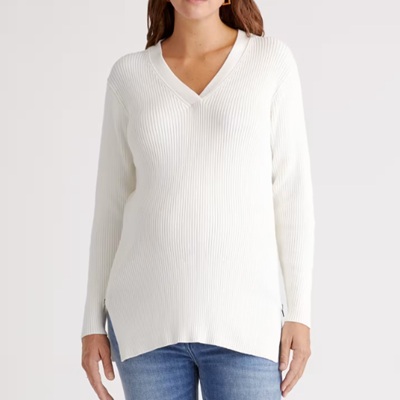 A woman wearing a white knitted sweater and denim pants
