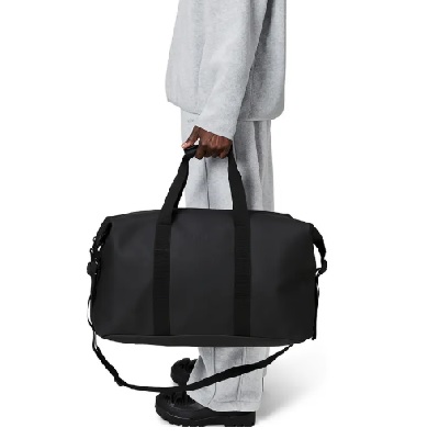 A woman dressed in gray carrying a black duffel