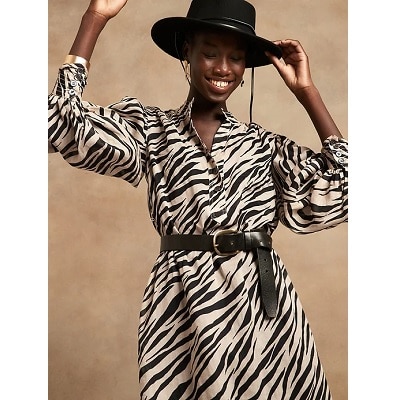 woman wearing animal print midi dress in white and black with a black hat