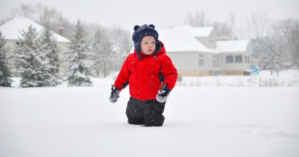 A young man riding a snowboard down a snow covered slope