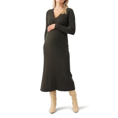 A pregnant woman wearing a dark olive nursing dress and tan boots