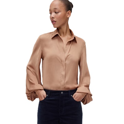 A woman wearing a brown satin blouse and black pants