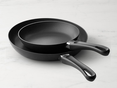 Two black frying pans on a marble surface