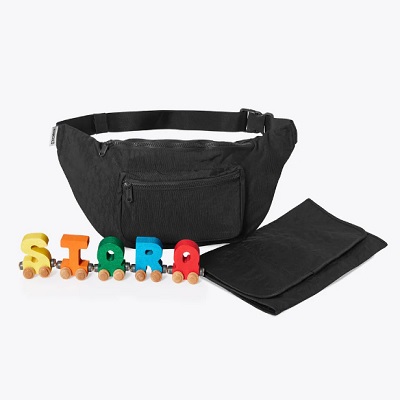 A black fanny pack next to a black wallet and toy wooden train with each car spelling out "STORQ"