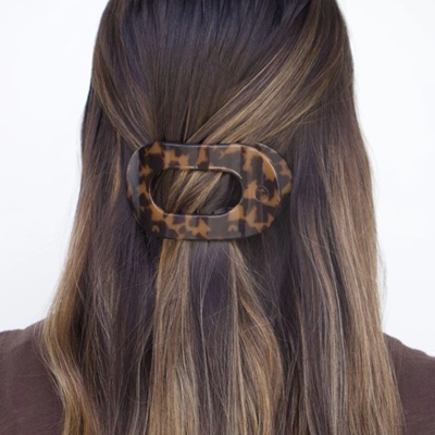 A woman with brown hair and brown shirt wearing a tortoiseshell hair clip