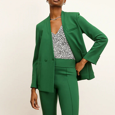 A woman wearing an M.M.LaFleur green suit and green printed blouse 