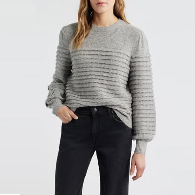 A woman wearing a gray sweater and black jeans