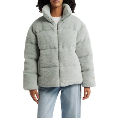 A woman wearing a gray puffer jacket and light blue jeans