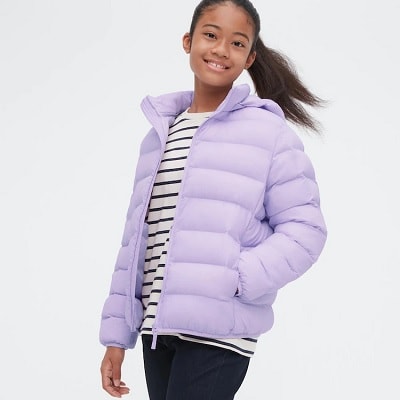 A girl wearing a lavender winter coat, striped shirt, and black pants