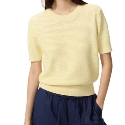 A woman wearing a yellow short-sleeved sweater and navy culottes