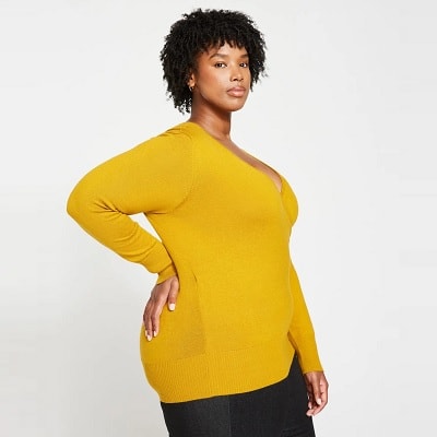 A woman wearing a yellow sweater and black pants