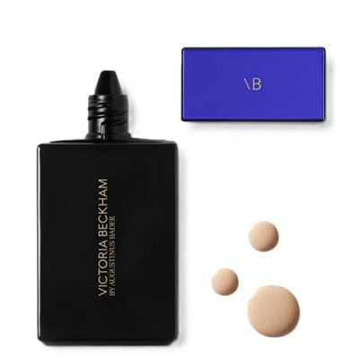 A container of Victoria Beckham Beauty Foundation Drops next to three swatches of shades