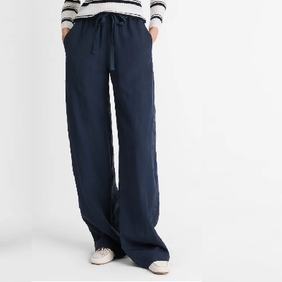 A woman wearing navy pants, a white-and-navy striped top, and white loafers