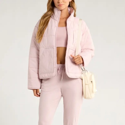 A woman wearing a pink bralette and pink quilted jacket with pink pants
