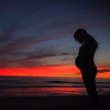 A picture of a pregnant woman at sunset.