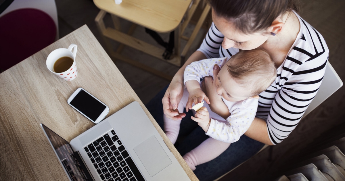 working mom holding baby on her lap while working at a computer