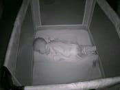 An image of a child sleeping while monitored by a baby-camera
