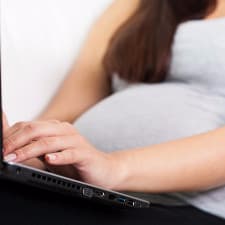 A pregnant woman using a laptop.