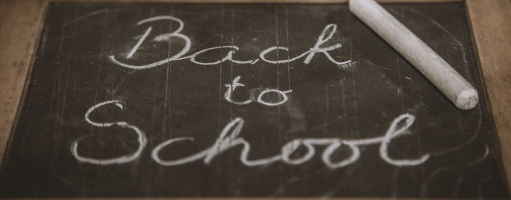 black chalkboard says "Back to School" written in cursive with white chalk