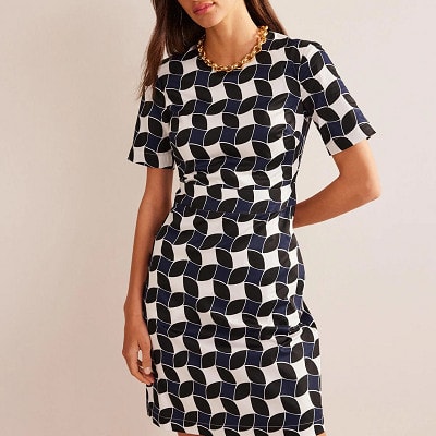 woman wears the machine-washable Alexa dress from Boden in a navy/white print
