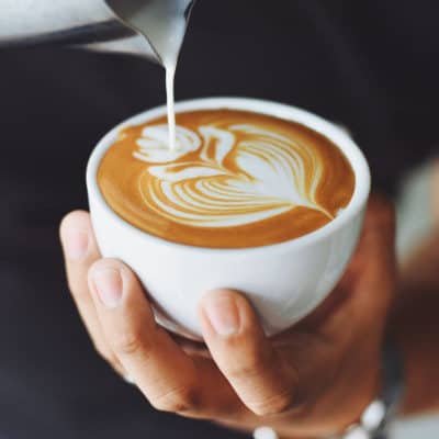 A close up of a person holding a cup of coffee