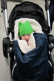 A child wearing a green beanie sitting in a stroller