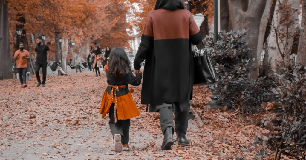 A woman with a child walking down a street