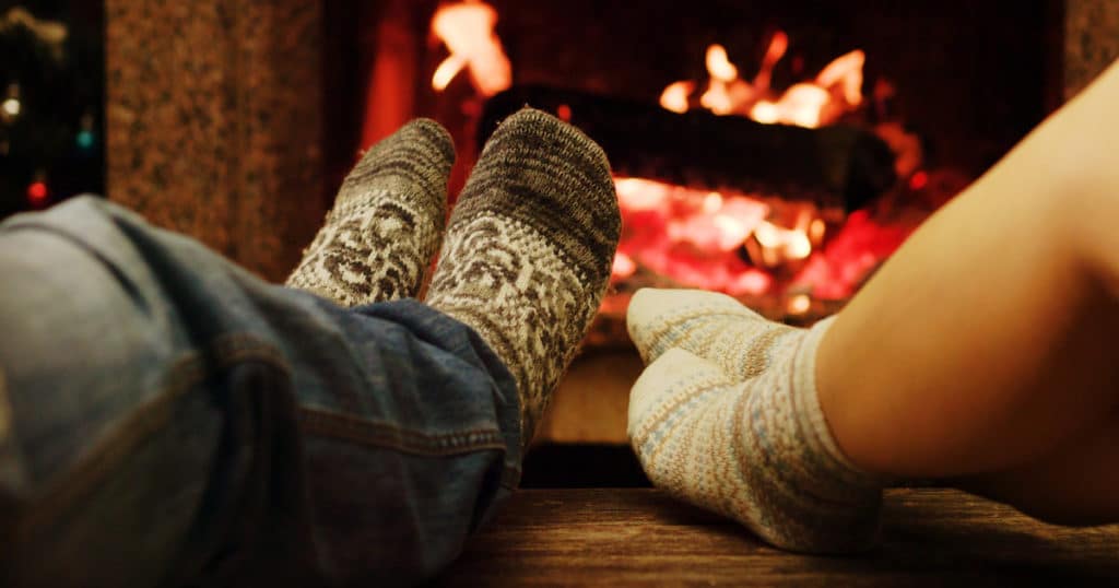 Two persons warming their toes by the fireplace