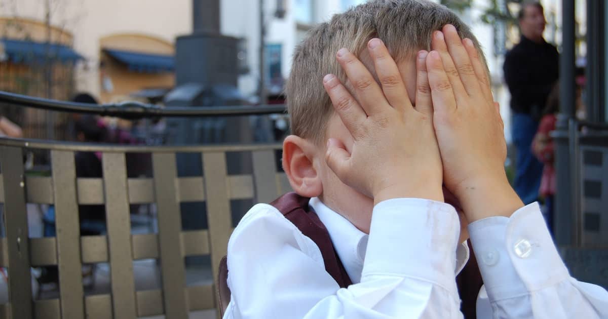 young boy with his hands over his face