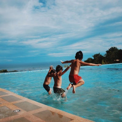 Three children jumping on a pool